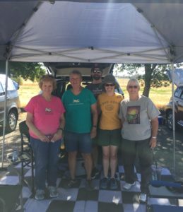 Five adults standing under a canopy