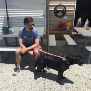 Man sitting on bench, holding a pink leash with a dog on it