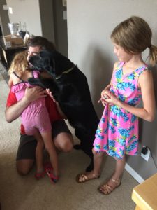 Two people and a Labrador hugging